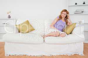 Good looking red-haired woman on the phone sitting on a sofa