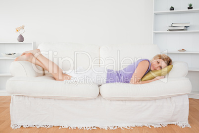 Beautiful woman posing and smiling while lying on a sofa