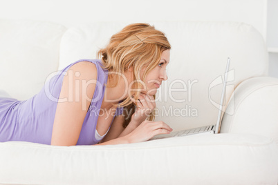 Young beautiful red-haired woman with a laptop on a sofa Young beautiful red-haired woman with a laptop on a sofa