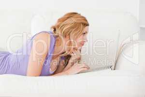 Young beautiful red-haired woman with a laptop on a sofa