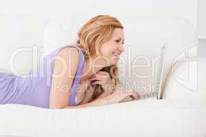 Young good looking red-haired woman with a laptop on a sofa