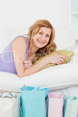 Smiling woman lying on the couch with her shopping bags