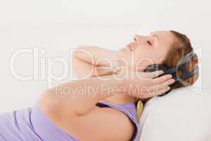 Lovely blond-haired woman listening to music lying on the sofa