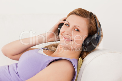 Beautiful blond-haired woman listening to music lying on the sof