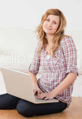 Young woman looking at the camera while surfing on her laptop