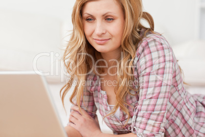 Cute woman working on her laptop lying down on the floor