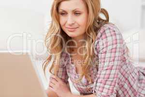 Cute woman working on her laptop lying down on the floor
