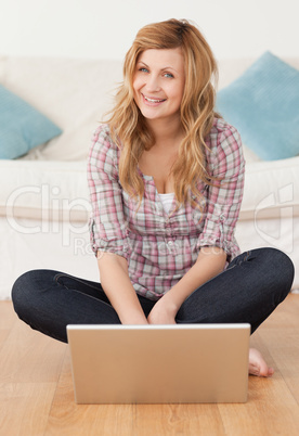 Smiling woman looking at the camera while surfing on her laptop