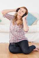Cute woman listening to music while sitting on the floor
