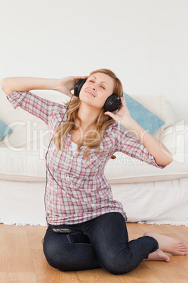 Happy woman listening to music while sitting on the floor