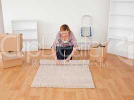 Blonde woman rolling up a carpet to prepare to move house