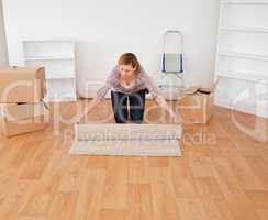 Blond-haired woman rolling up a carpet to prepare to move house
