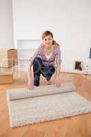 Young woman rolling up a carpet to prepare to move house