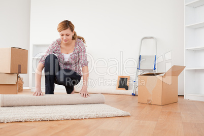 Lovely woman rolling up a carpet to prepare to move house