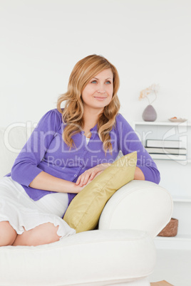Serene red-haired woman posing while sitting on a sofa