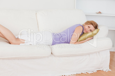 Smiling blonde woman resting while lying on the sofa