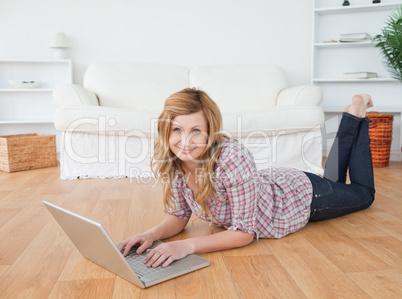 Cute woman looking at the camera while chatting on her laptop