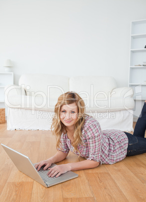 Blonde woman looking at the camera while chatting on her laptop