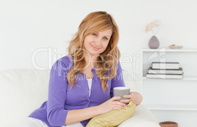 Attractive red-haired woman posing while sitting on a sofa