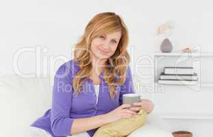 Attractive red-haired woman posing while sitting on a sofa