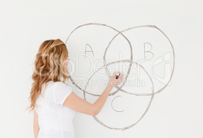 Blond-haired teacher drawing a scheme on a white board