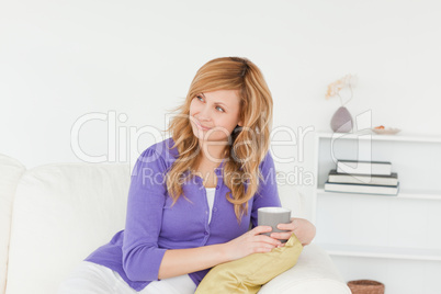 Pretty red-haired woman looking at something while sitting on a