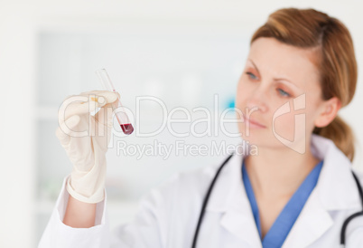 Blond-haired scientist looking at a red test tube