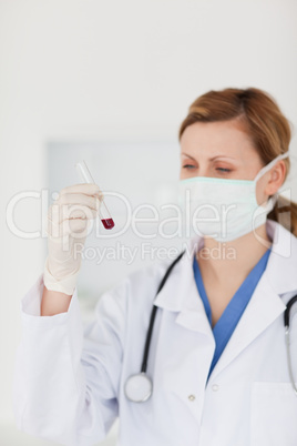 Blond-haired scientist with a mask looking at a test tube