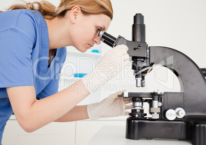 Female scientist conducting an experiment looking through a micr