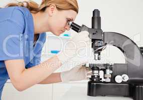 Female scientist conducting an experiment looking through a micr