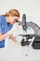 Cute female scientist looking through a microscope