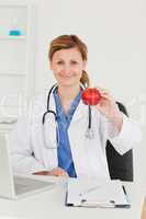 Cute female doctor showing an apple to the camera