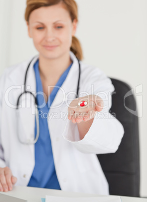 Blond-haired female doctor showing pills to the camera