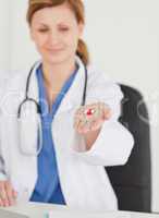 Blond-haired female doctor showing pills to the camera