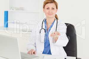 Smiling female doctor showing pills to the camera
