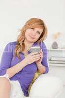 Attractive red-haired woman holding a cup of coffee while sittin