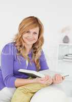 Pretty red-haired woman reading a book and posing while sitting