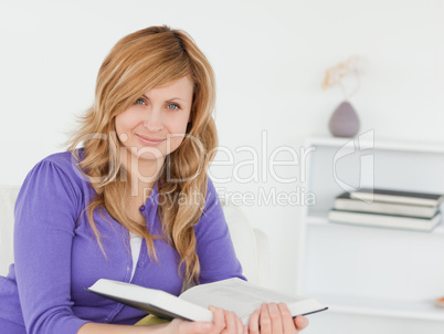 Portrait of a beautiful red-haired woman reading a book and posi