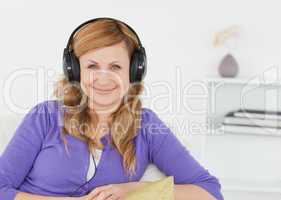 Beautiful red-haired woman listening to music and posing while s