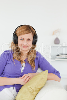 Pretty red-haired woman listening to music and posing while sitt