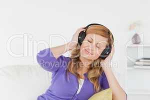 Pretty red-haired woman listening to music and enjoying the mome