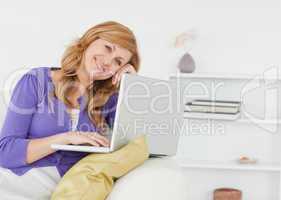 Smiling happy woman sitting on the sofa and using a laptop