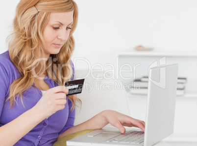 Concentrated woman sitting on a sofa is going to make a payment