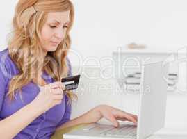 Concentrated woman sitting on a sofa is going to make a payment