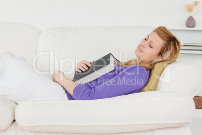 Pretty woman lying on the sofa who has fallen asleep while readi
