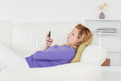 Profile portrait of a red-haired woman writing a text message wh