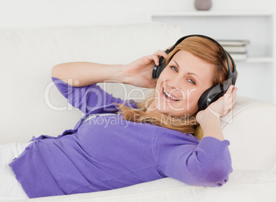 Joyful red-haired woman listening to music