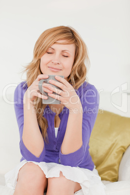 Beautiful red-haired woman holding and smelling a cup of coffee