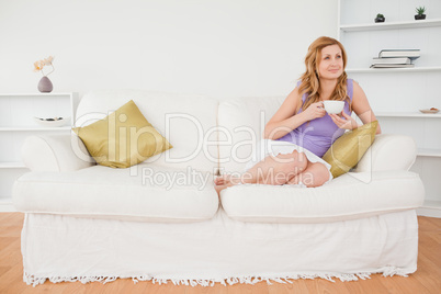 Pensive red-haired woman holding a cup of coffee