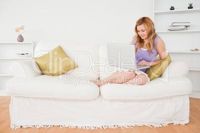 Beautiful  woman sitting on a sofa and using a laptop